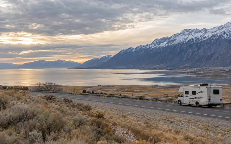 An RV on a Provo frontage road, on the broad lake plain with the mountain wall to the east