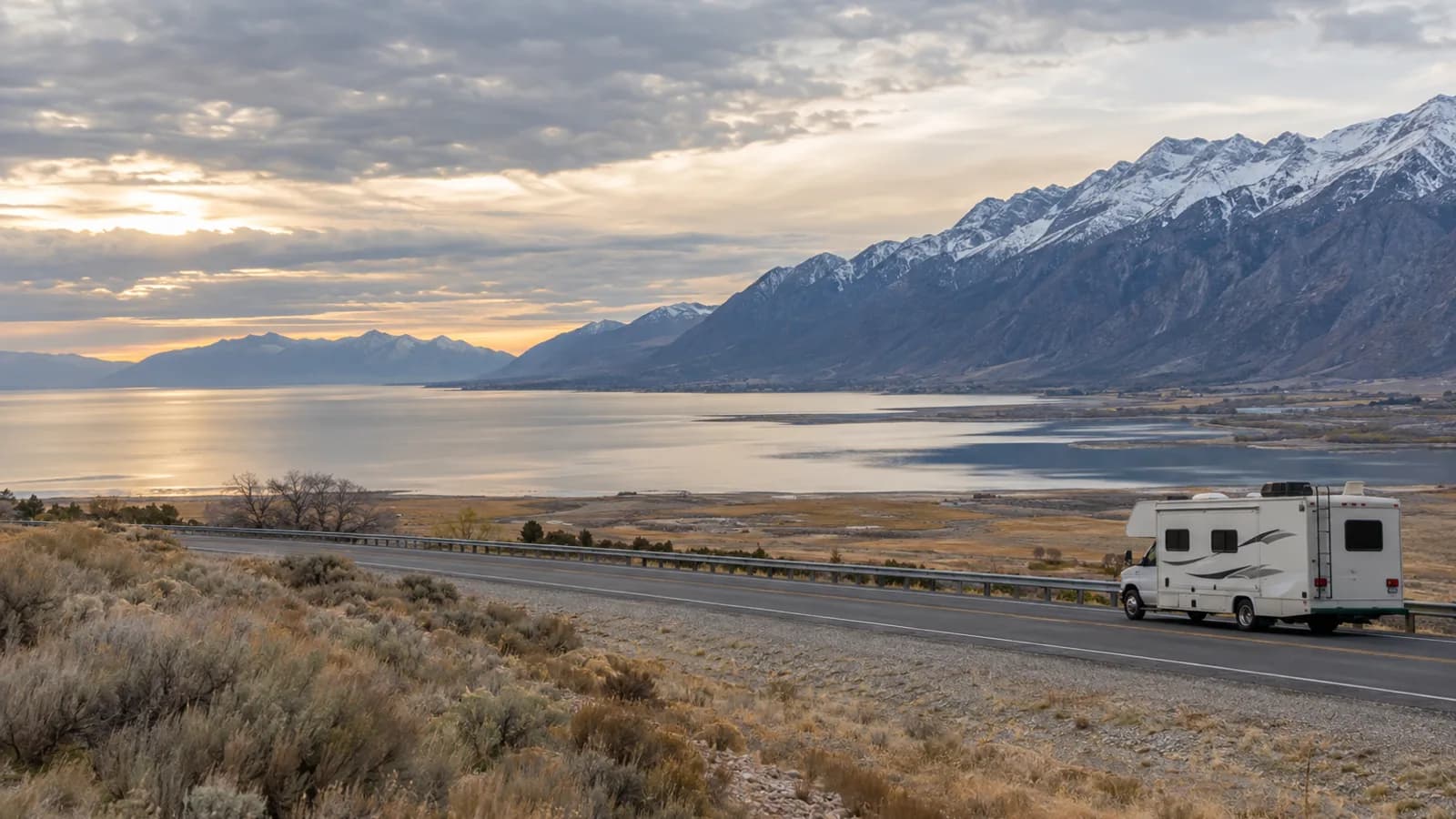 a broad lake plain south of the valley with a long mountain wall east, an RV on a frontage road