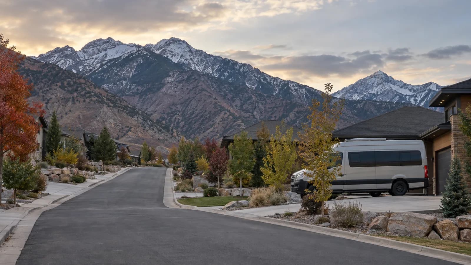 suburban foothill street rising toward the mountain front, a camper van on a driveway