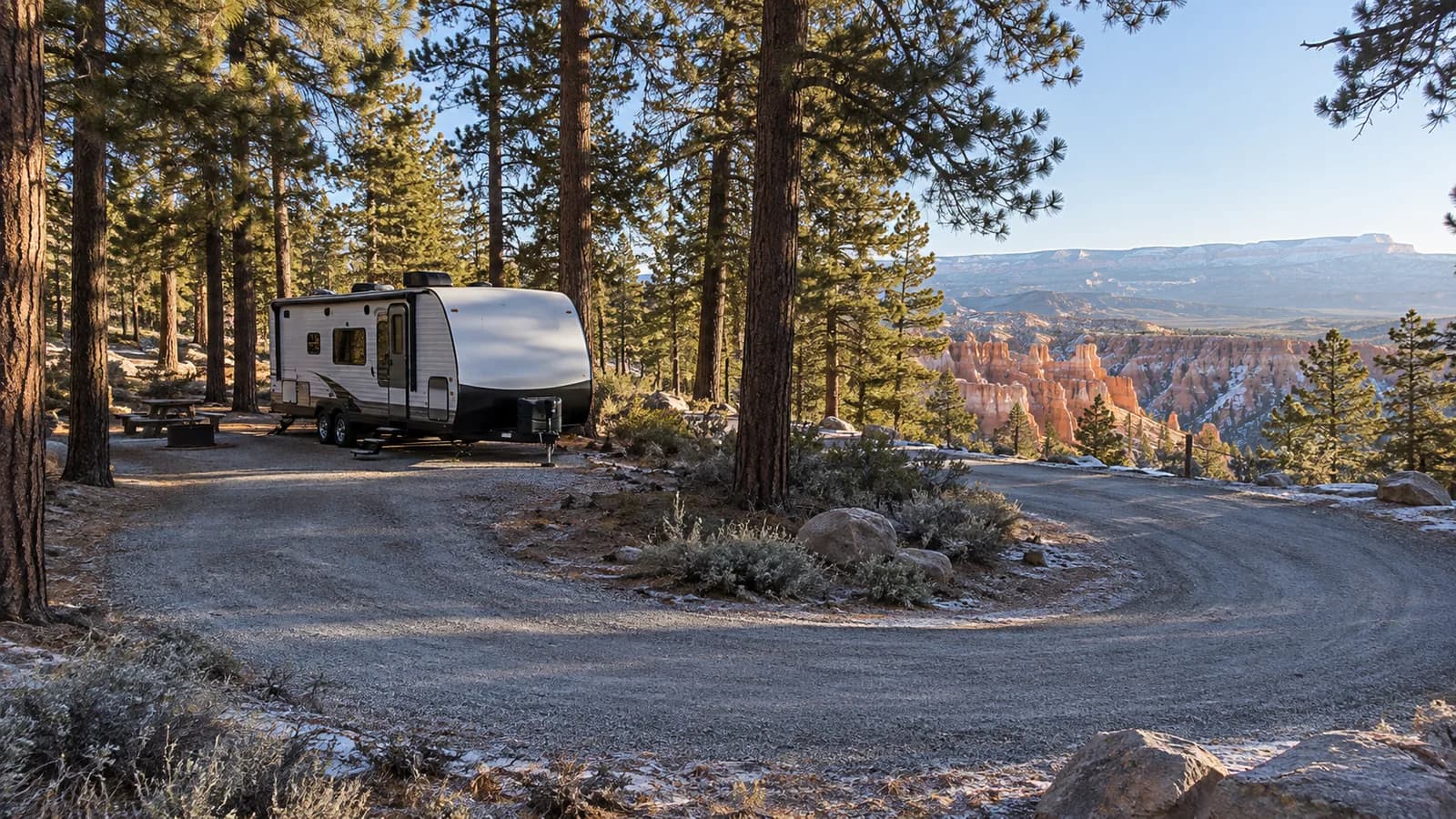 A travel trailer parked in a pine-shaded campground loop on the rim above Bryce hoodoos