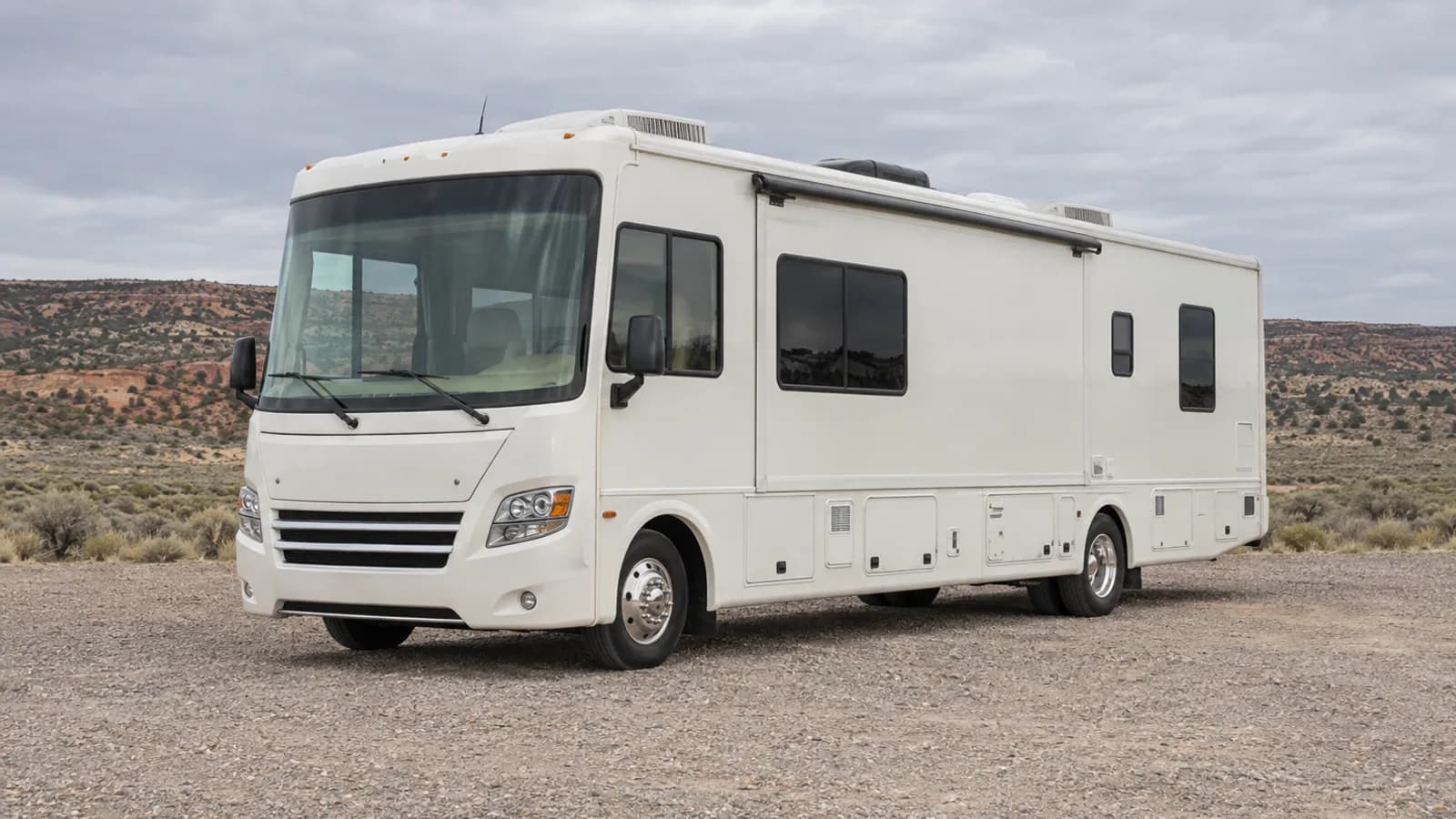 A Class A bus-style motorhome photographed from the front three-quarter angle for size comparison