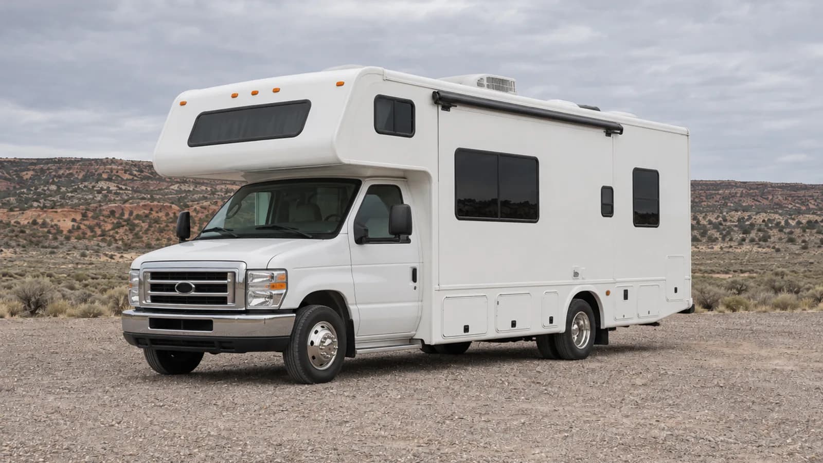 A Class C motorhome with over-cab sleeping bunk photographed from the front three-quarter angle for size comparison